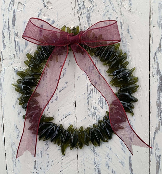 a handmade green glass wreath from a recycled wine bottle with a red ribbon bow