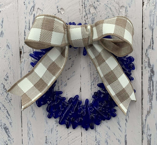 a handmade blue recycled glass wreath with a tan and white plaid bow