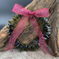 a handmade green glass wreath from a recycled wine bottle with a red and white plaid ribbon bow