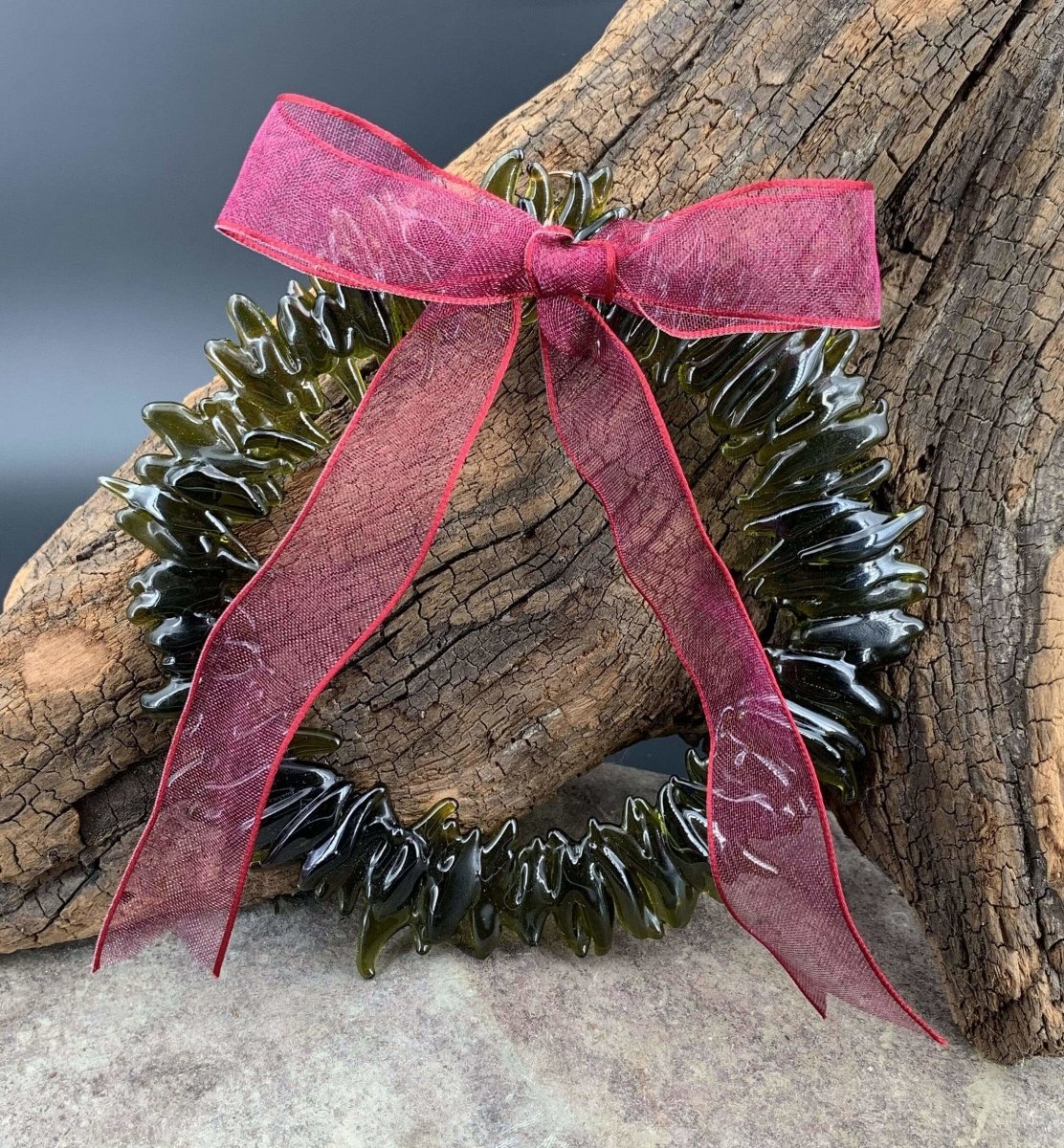 a handmade green glass wreath from a recycled wine bottle with a red ribbon bow