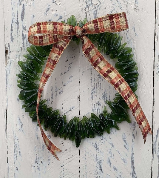 a handmade green glass wreath from a recycled wine bottle with a red and white plaid ribbon bow
