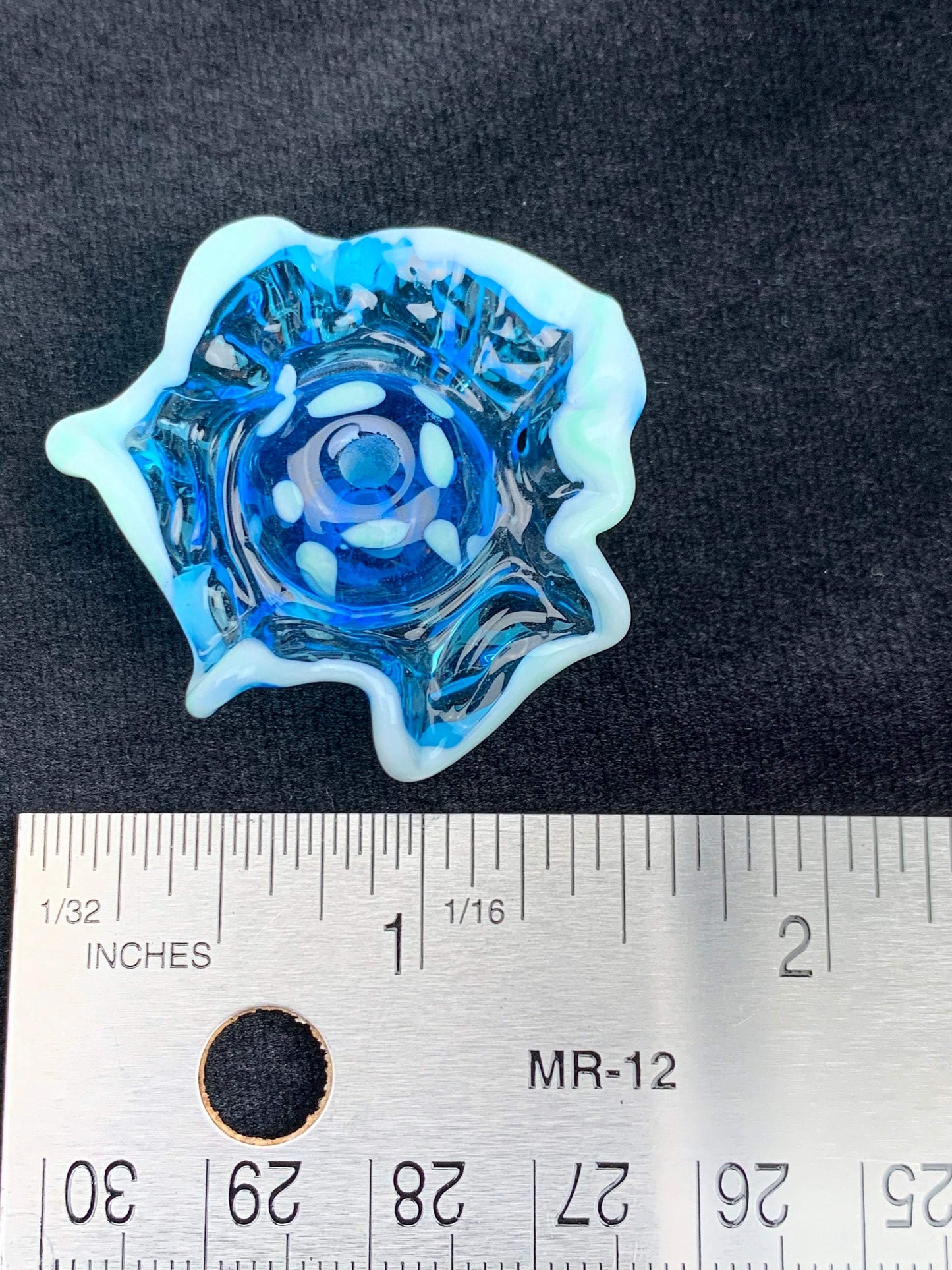 a handmade lampworked blue glass bead with a blue glass ruffle with white dots around the middle of the bead.