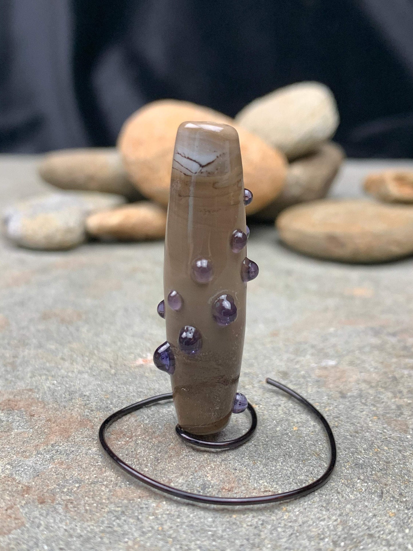 a handmade lampworked glass bead with purple dots on sage gray background