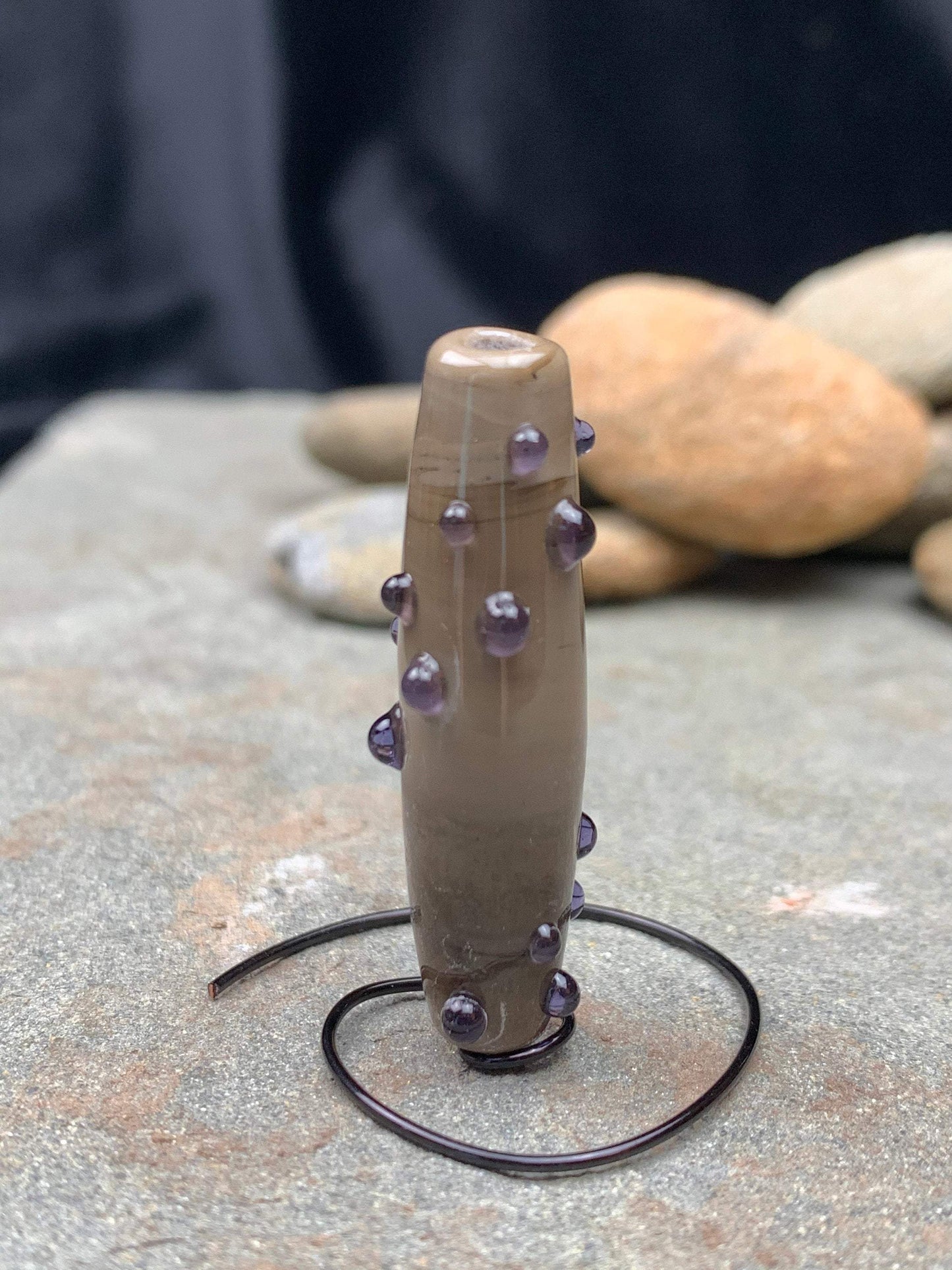 a handmade lampworked glass bead with purple dots on sage gray background