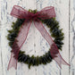 a handmade green glass wreath from a recycled wine bottle with a red ribbon bow