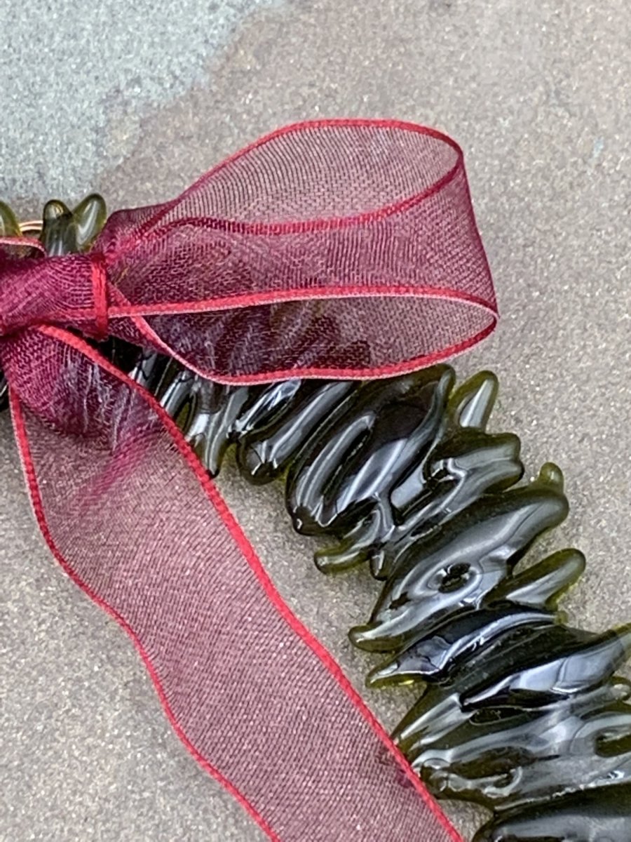 a handmade green glass wreath from a recycled wine bottle with a red ribbon bow