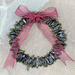 a handmade green glass wreath from a recycled wine bottle with a red ribbon bow