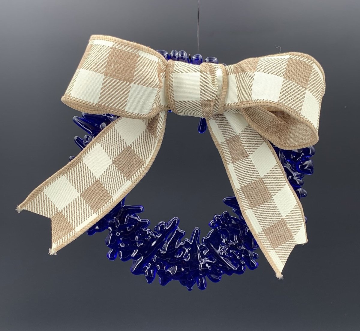 a handmade blue recycled glass wreath with a tan and white plaid bow