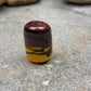 a handmade lampworked glass bead with black stripe on a yellow and brown background