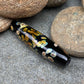 a handmade lampworked glass bead with multicolor dots on a black background