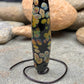 a handmade lampworked glass bead with multicolor dots on a black background