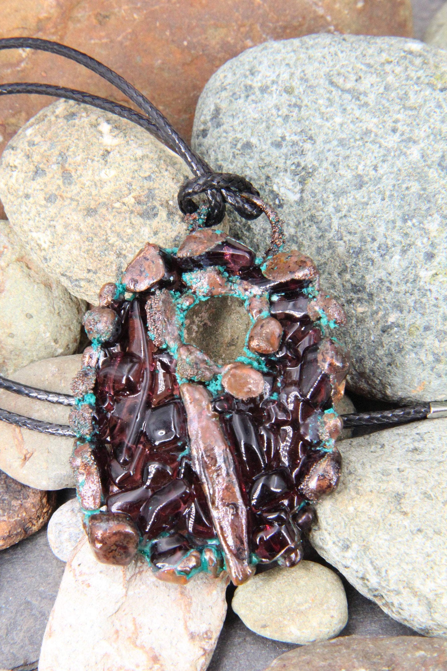 a handmade pendant from recycled glass that has been electroformed with copper and had a patina applied