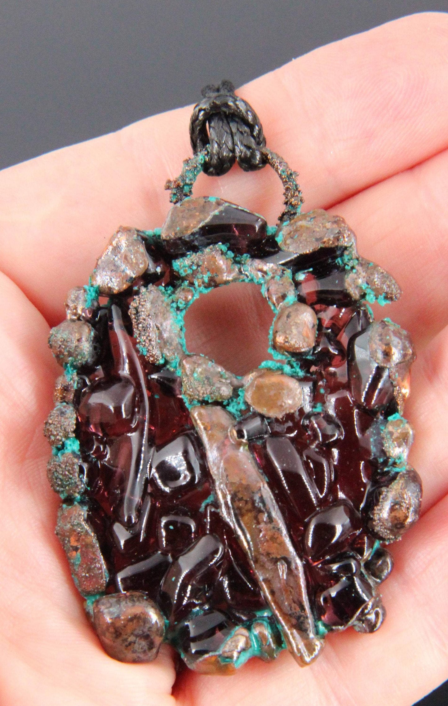 a handmade pendant from recycled glass that has been electroformed with copper and had a patina applied